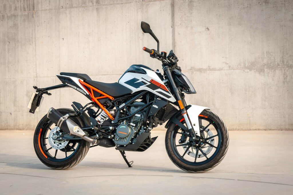 A sleek motorcycle parked against a concrete wall in an urban environment, showcasing modern design.