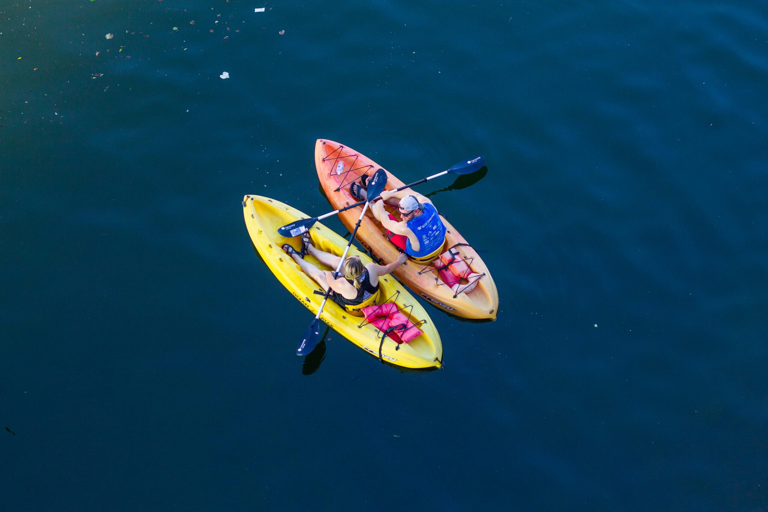 Energized couple kayaking on tranquil ocean surface, top view enhancing connection.