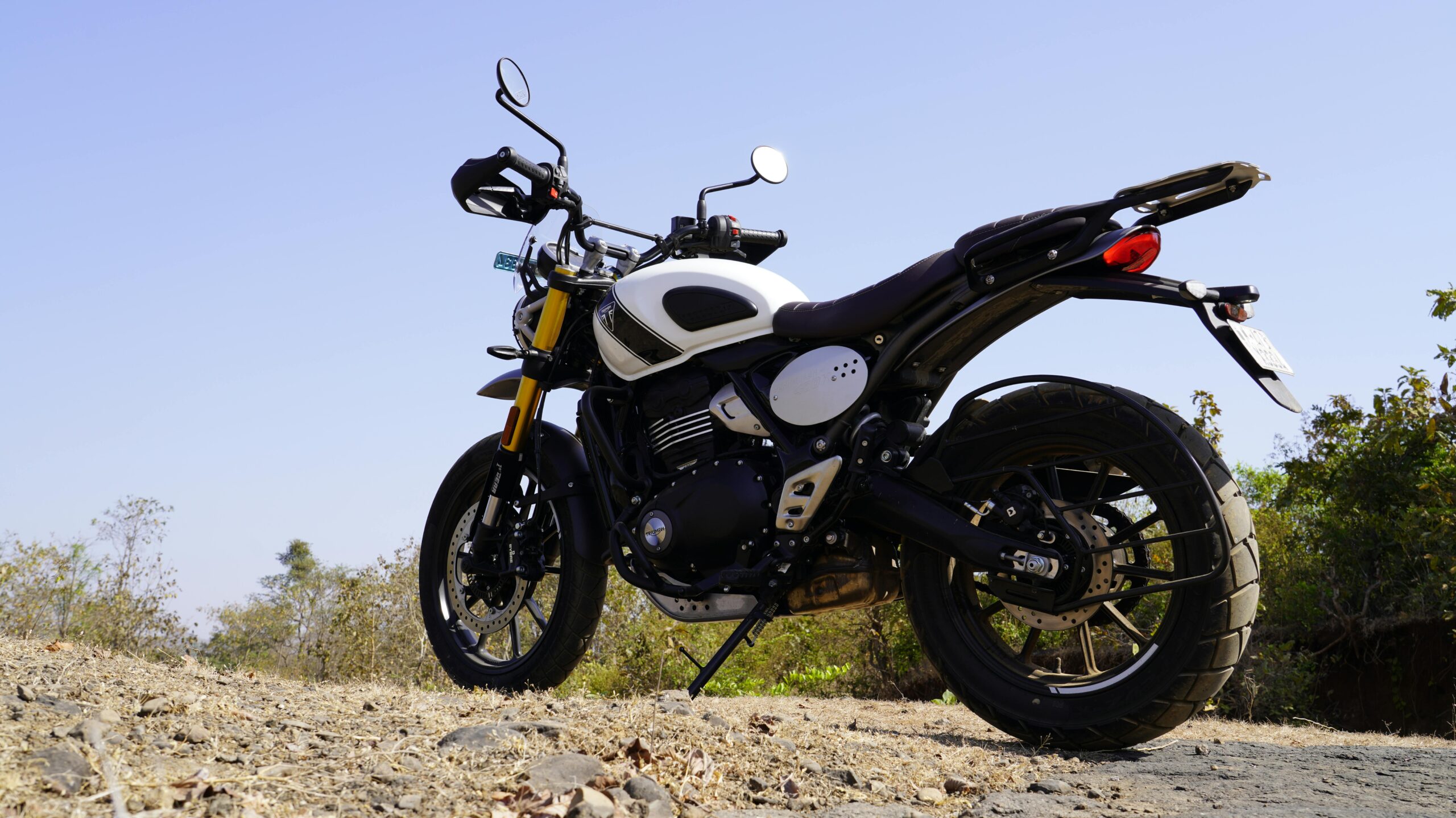 A sleek black and white motorcycle parked on a rocky outdoor terrain under a clear blue sky.