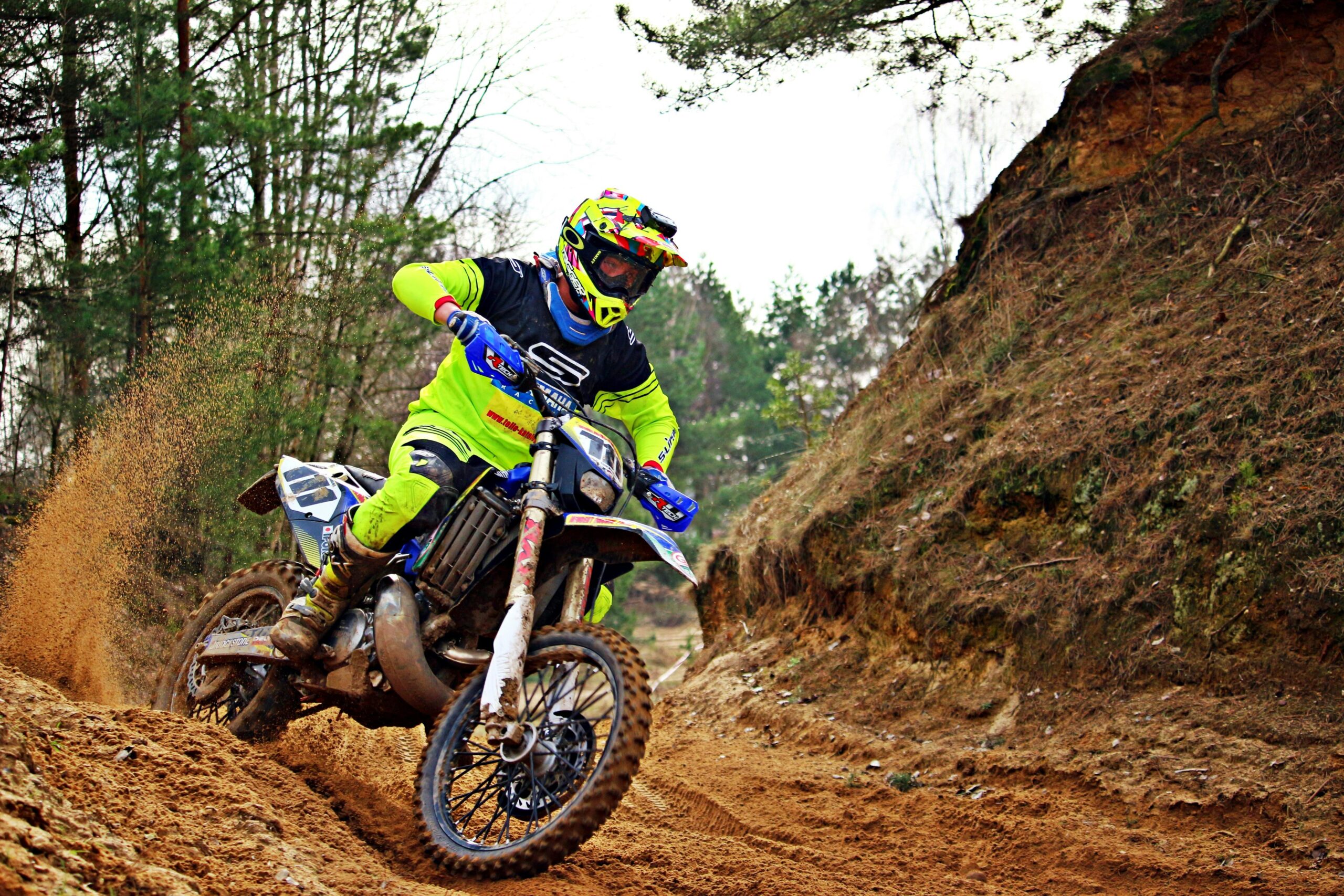 Exciting motocross action shot of a biker speeding through a forest trail, showcasing skill and intensity.