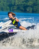 Man enjoying an exhilarating jet ski ride on water, capturing a splash of summer excitement.