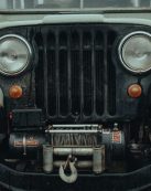 Close-up of a rugged vintage jeep showcasing its front grill and headlights. Perfect for adventurous themes.