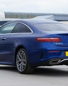 Elegant blue sports coupe car displayed in an urban parking lot, showcasing luxury and style.