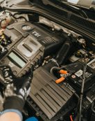 Close-up view of a mechanic diagnosing a Volkswagen engine with specialized equipment.