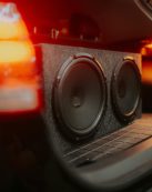 Close-up of dual subwoofers in a car trunk with glowing lights.