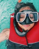 Relaxed individual floating in clear blue waters, wearing snorkeling gear and a life jacket.