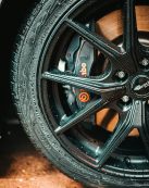 Detailed photo of a black alloy wheel with visible water droplets and a prominent Brembo brake caliper.