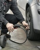 Mechanic inspecting and adjusting tire pressure in an auto repair shop.