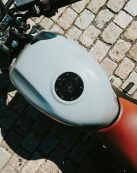Top view of a motorcycle with focus on the fuel tank and handlebars on a cobblestone street.