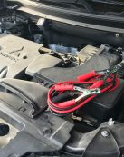 Detailed view of a car engine with red jumper cables, ideal for automotive themes.
