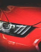 Detailed view of a red Ford Mustang's headlight showcasing sleek automotive design.