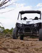 White off-road utility vehicle conquering rugged terrain outdoors under a bright sky.