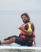 Man with prosthetic leg paddleboarding in Portugal's calm bay waters.